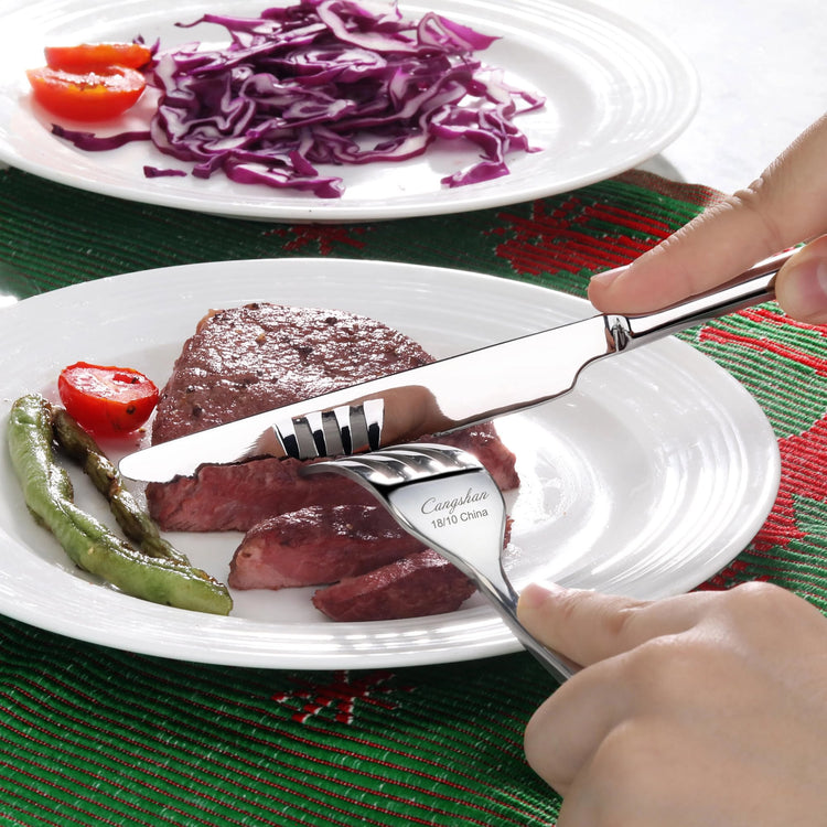 Person cutting a cooked steak with a RAIN II Series Dinner Knife, Forged Stainless Steel, Mirror Finish, 505026 on a white pl