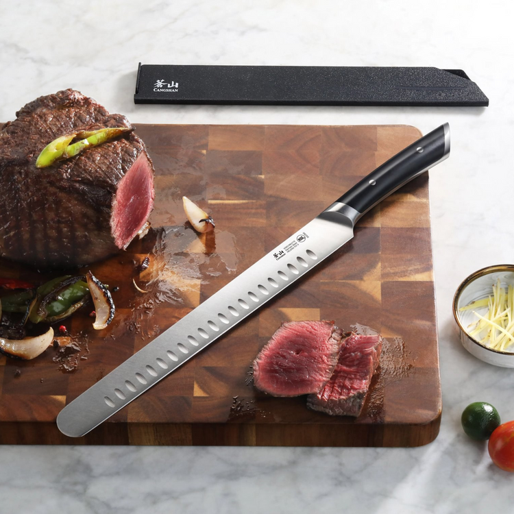11-inch slicing knife with black handle on wooden cutting board next to sliced cooked meat and vegetables.