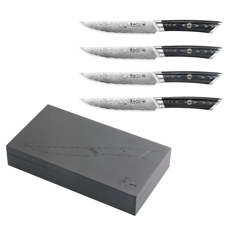 Four steak knives with patterned blades and black handles displayed above a closed black wooden box with engraved design.