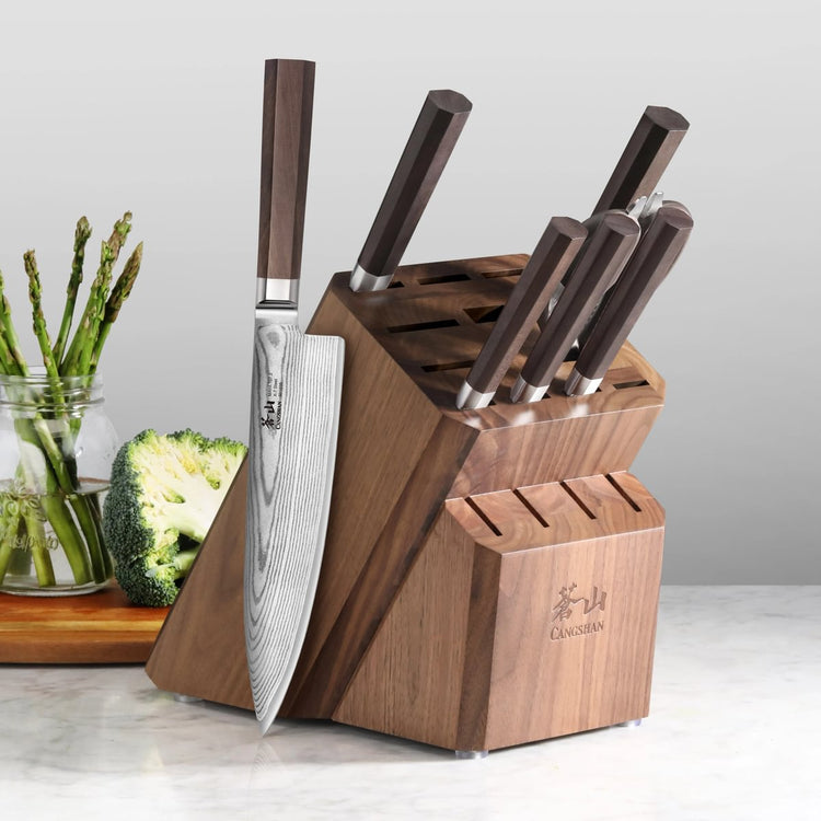 Eight-piece knife set with Damascus steel blades and walnut handles in a wooden block on a kitchen counter.