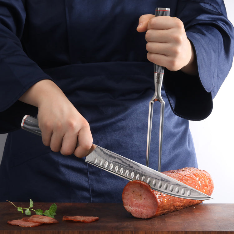 Person wearing a dark blue apron slicing a large piece of cured meat with a carving knife and fork on a wooden board.