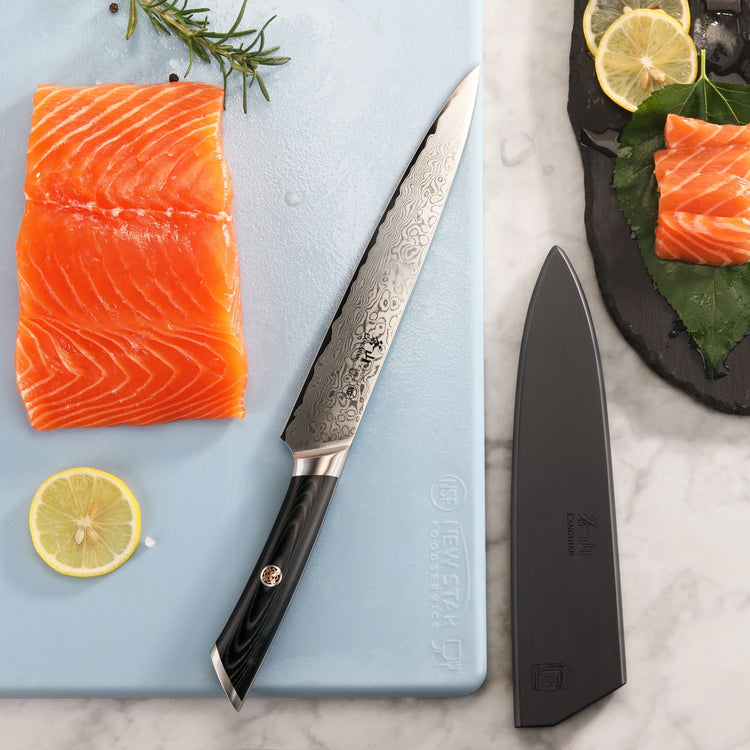 8-inch Damascus steel knife with black handle next to a salmon fillet, lemon slices, and a black sheath on a marble surface.