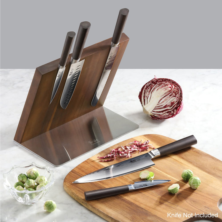 Magnetic wooden knife block holding three knives, with two knives and chopped radicchio on a cutting board nearby.