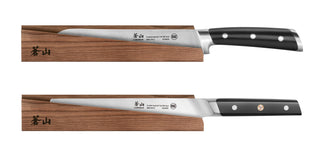
                    
                      Two kitchen knives with black handles resting on solid ash wood magnetic sheaths with Japanese characters.
                    
                  