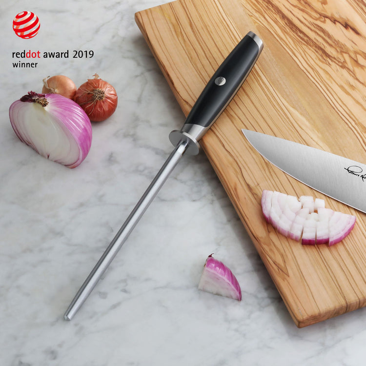 Diamond-coated honing steel with black handle on marble surface next to a wooden cutting board, sliced onion, and knife.