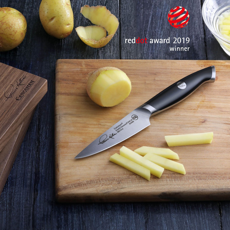 3.5-inch paring knife with black handle on wooden cutting board, slicing peeled potatoes into sticks.