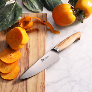 
                    
                      6-inch chef's knife with wooden handle on a cutting board next to sliced and peeled persimmons.
                    
                  