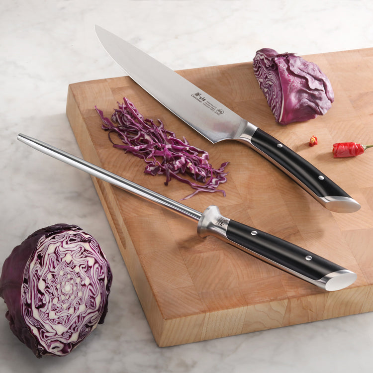 8-inch honing steel with black handle and chef's knife on wooden cutting board with sliced red cabbage.