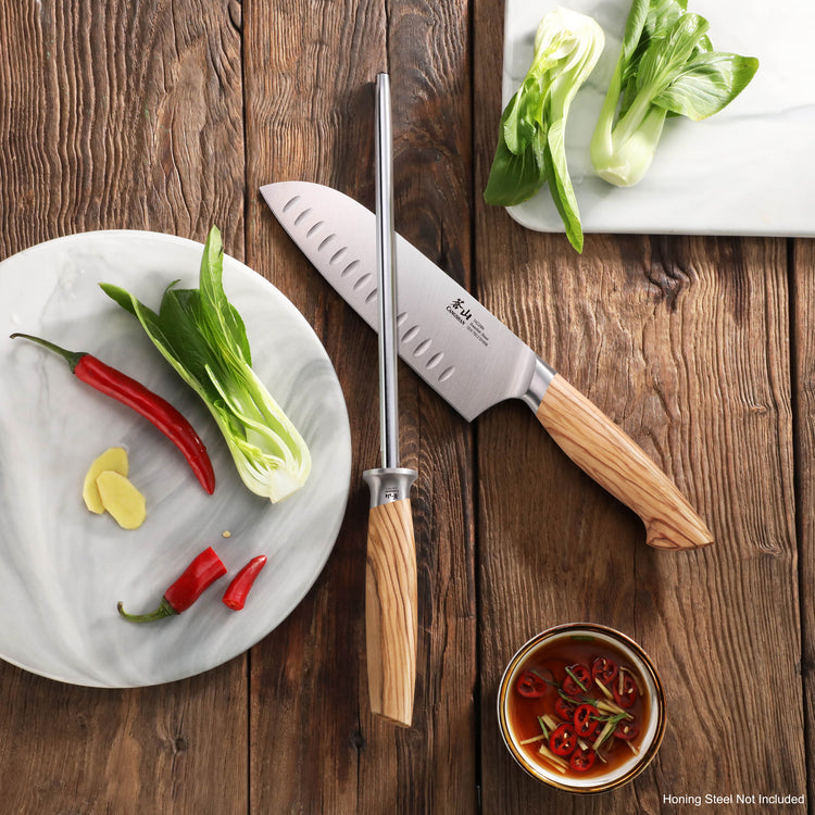 7-inch Santoku knife with olivewood handle and sharpening steel on wooden surface with bok choy, chili peppers, and dipping s